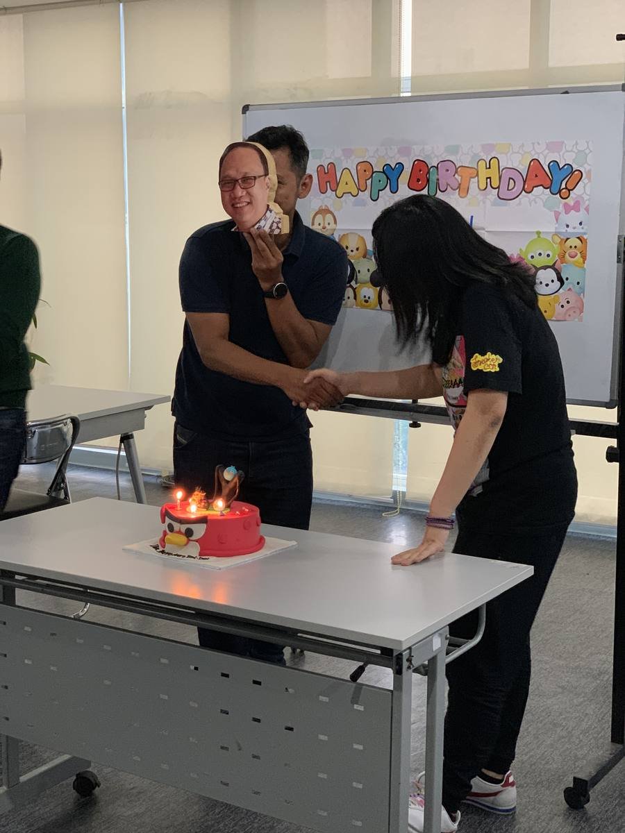 Perayaan ulang tahun di kantor dengan kue dan papan ucapan